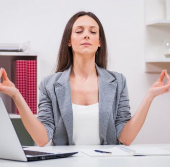 image of a woman practicing yoga at her desk
                  